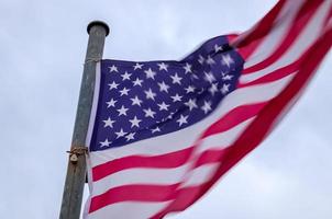 bandera de estados unidos en un asta de bandera moviéndose lentamente en el viento contra el cielo foto