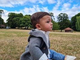 lindo bebé pequeño está posando en un parque público local de la ciudad de luton de inglaterra reino unido foto