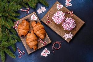 croissant de chocolate crujiente con adornos navideños en tabla de cortar de madera foto