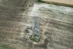 High Voltage Power Supply Poles with Cables Running Through British Farmlands and Countryside, Aerial high angle view by drone's camera. photo