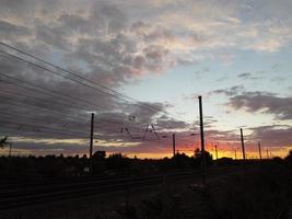 hermosa puesta de sol sobre la ciudad británica, cielo colorido con nubes amarillas, naranjas y negras sobre el cielo azul claro foto