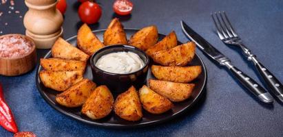 gajos de patata al horno con queso y hierbas y salsa de tomate sobre un fondo oscuro foto