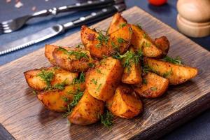 Baked potato wedges with cheese and herbs and tomato sauce on a dark background photo