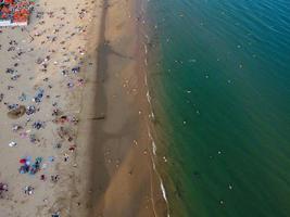 Frente a la playa con vistas al mar en ángulo alto con gente en la ciudad de Bournemouth, Inglaterra, Reino Unido, imágenes aéreas del océano británico foto