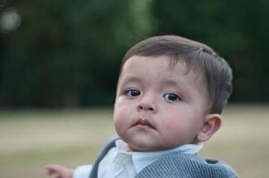 lindo bebé pequeño está posando en un parque público local de la ciudad de luton de inglaterra reino unido foto