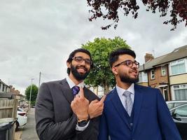 Los hombres jóvenes jóvenes empresarios están posando en una calle de Luton, Inglaterra foto