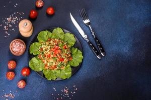 Plate of salad with vegetables and greens on a dark concrete table photo