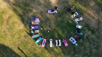 grupo de mujeres ejerciendo yoga juntas en el parque público al atardecer del caluroso verano, vista aérea de ángulo alto del parque wardown luton inglaterra reino unido foto