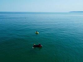 High Angle Footage and Aerial view of Ocean with High Speed Boats, People are having fun and enjoying hottest weather at Bournemouth Beach Sea Front of England UK. photo