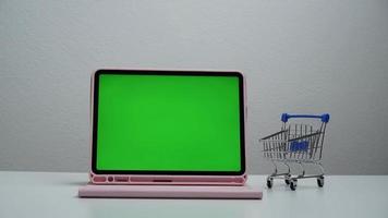 Stoppen Sie die Bewegung eines Einkaufswagens, der sich auf dem grünen Bildschirm des Tablets bewegt. video