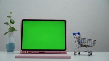 stop motion un panier shopping se déplaçant autour de l'écran vert de la tablette. video