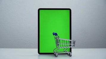 Stoppen Sie die Bewegung eines Einkaufswagens, der sich auf dem grünen Bildschirm des Tablets bewegt. video