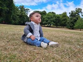 lindo bebé pequeño está posando en un parque público local de la ciudad de luton de inglaterra reino unido foto