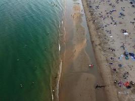 Frente a la playa con vistas al mar en ángulo alto con gente en la ciudad de Bournemouth, Inglaterra, Reino Unido, imágenes aéreas del océano británico foto