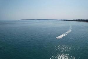 High Angle Footage and Aerial view of Ocean with High Speed Boats, People are having fun and enjoying hottest weather at Bournemouth Beach Sea Front of England UK. photo