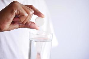 holding a Effervescent soluble tablet pills and glass of water photo