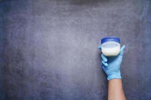 top view of hand in latex gloves holding a petroleum jelly container photo