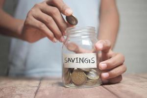 child boy hand hold a saving coins jar photo