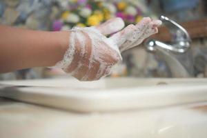 young man washing hands with soap warm water photo