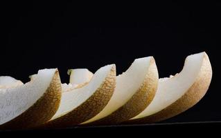 A row of lobes of ripe juicy melon on a black background.. photo