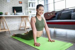 joven asiática haciendo ejercicio y haciendo yoga en la pose de cobra en casa, concepto saludable.