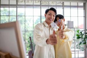 Asain gay couple draw and paint together in the living room of their home, LGBTQ concept. photo