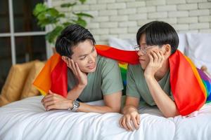 Happy asian gay couple talking together and relaxing at home on bed, LGBTQ concept. photo