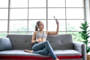 Young Asian woman using smratphone at home, feel relax and enjoy communicate and discuss  in living room. photo