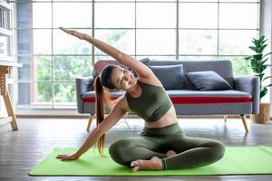 joven asiática haciendo ejercicio y haciendo yoga en casa, concepto saludable. foto