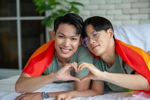 Happy asian gay couple talking together and relaxing at home on bed, LGBTQ concept. photo