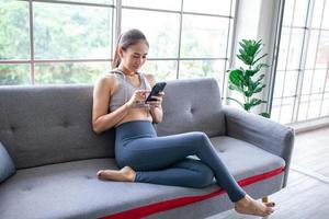 Young Asian woman using smratphone at home, feel relax and enjoy communicate and discuss  in living room. photo