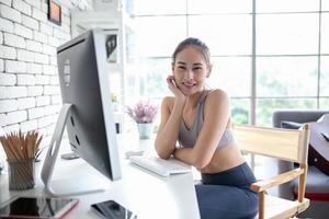 Young Asian woman using laptop computer checking social media application on website online at home, feel relax and enjoy communicate and discuss  in living room. photo