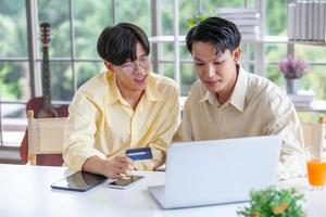 Asian gay couples are using laptop or shopping online with credit card,  LGBTQ concept. photo