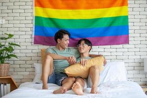 Happy asian gay couple holding hands together relaxing at home on bed, LGBTQ concept. photo