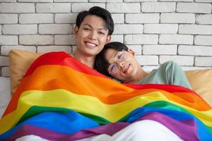 Happy asian gay couple talking together and relaxing at home on bed, LGBTQ concept. photo