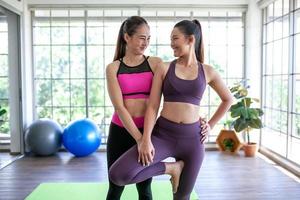 young asian woman working out and doing yoga in the tree pose at home, healthy concept. photo