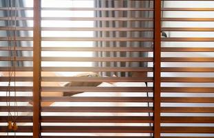 Wooden Venetian blinds. Blackout curtain between bathroom and bedroom in hotel with back view of woman sleep under white blanket on bed in the morning. Jalousie or window blinds. Horizontal blinds. photo