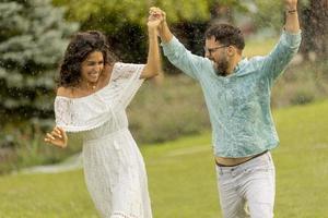 Joyful young couple caught by the summer rain in the park photo