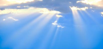 The sun's rays break through the blue clouds. The background of the sky. photo