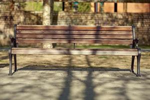 Wooden bench illuminated by bright sunlight in the park. photo