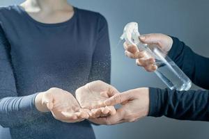 Women's hands are treated with a sanitizer girl's hands on a gray background. photo