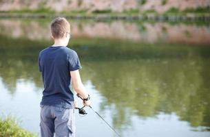 joven pescando en el lago con caña. concepto de estilo de vida de viaje vacaciones de verano. foto