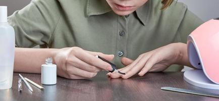 The girl makes her own manicure gel Polish. Concept of hand care in conditions of self-isolation. photo