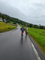 Two cycling male tourists moving rapidly on Norway fjords coastal road 7 photo