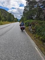 dos turistas masculinos en bicicleta moviéndose en la carretera costera de los fiordos de noruega 5 foto
