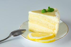 Piece of biscuit dessert  with lemon and coconut flakes. Layered vanilla cake on white plate. photo