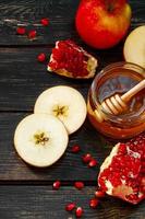 Traditional Jewish religious holiday Rosh Hashanah. Apples, pomegranates and honey on dark wooden background. Vertical photo. photo