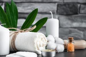 Wellness accessories on gray stone background. Towel, candles and aromatic salt.