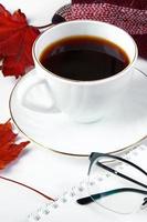 Warm checkered plaid and cup of hot espresso coffee on white background. Hello autumn concept. Fallen red leaves and drink for cold weather. photo