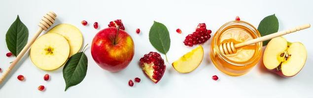 Happy Rosh Hashanah. Traditional Jewish holiday New Year. Apples, pomegranates and honey on white background. Banner format, place for text. photo
